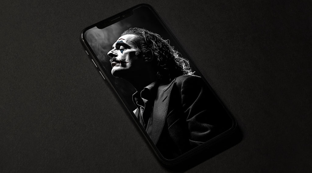 fond écran artistique du Joker en noir et blanc présentant une silhouette de profil dramatique en costume avec des effets de fumée, disponible en résolution HD et 4K.