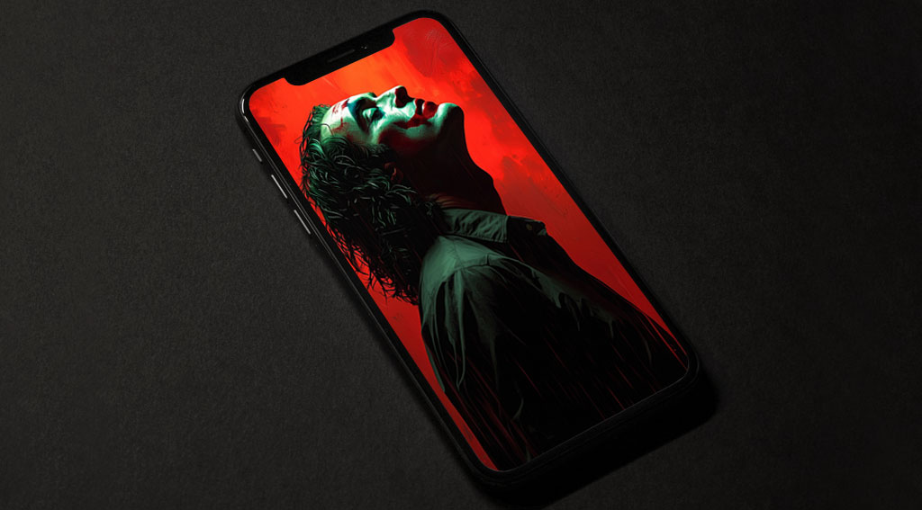 Fond d'écran Joker de Joaquin Phoenix 4K ultra HD avec fond rouge et pose emblématique du personnage, disponible en formats desktop et mobile haute résolution.