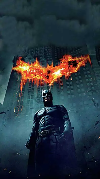 Batman The Dark Knight 4K wallpaper showing hero with giant flaming bat logo on Gotham building Ultra HD background free download