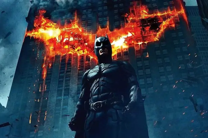 Batman The Dark Knight 4K wallpaper showing hero with giant flaming bat logo on Gotham building Ultra HD background free download