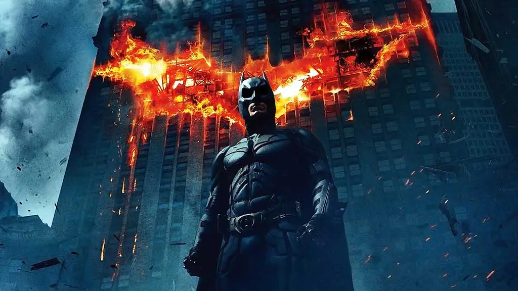 Batman The Dark Knight 4K wallpaper showing hero with giant flaming bat logo on Gotham building Ultra HD background free download