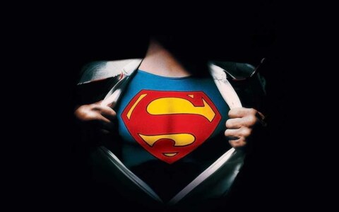 Superman logo reveal 4K wallpaper showing iconic red S shield costume under torn shirt HD superhero background