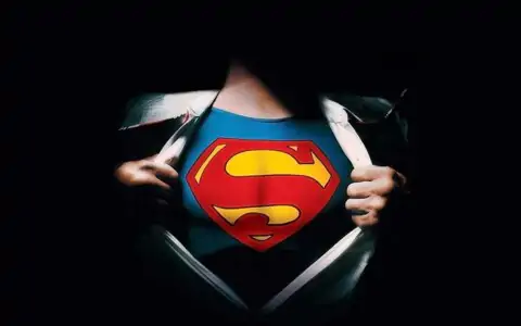 Superman logo reveal 4K wallpaper showing iconic red S shield costume under torn shirt HD superhero background