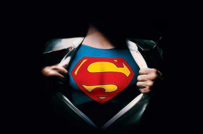 Superman logo reveal 4K wallpaper showing iconic red S shield costume under torn shirt HD superhero background
