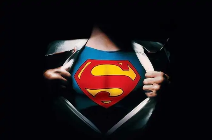 Superman logo reveal 4K wallpaper showing iconic red S shield costume under torn shirt HD superhero background